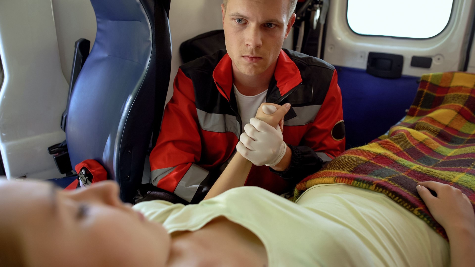 Male paramedic holding patient's hand, medical care and moral support, kindness